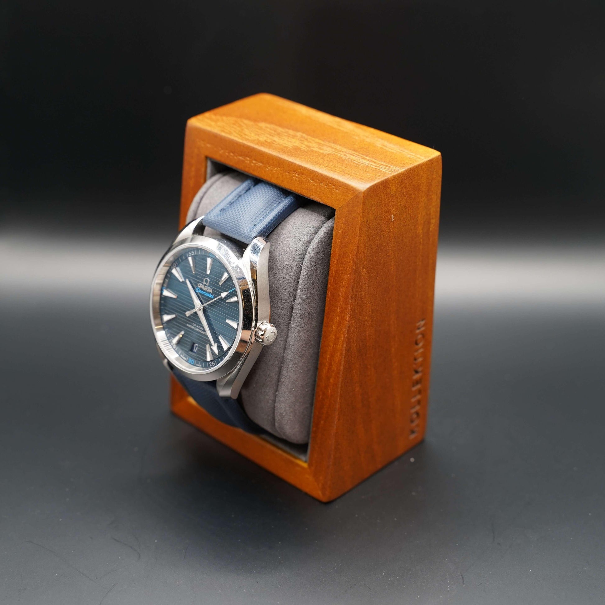 A grey wooden watch case with a microsuede interior. This stylish and functional case is made of high-quality materials and is available in both beige and grey.